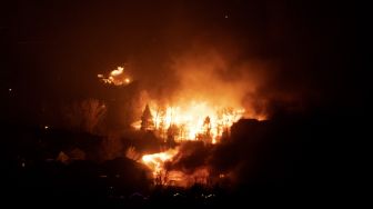 Api melahap rumah-rumah saat kebakaran Marshall menyebar melalui lingkungan di kota Superior, Boulder County, Colorado, Amerika Serikat, pada (30/12/2021). [JASON CONNOLLY / AFP]