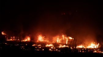 Api melahap rumah-rumah saat kebakaran Marshall menyebar melalui lingkungan di kota Superior, Boulder County, Colorado, Amerika Serikat, pada (30/12/2021). [JASON CONNOLLY / AFP]