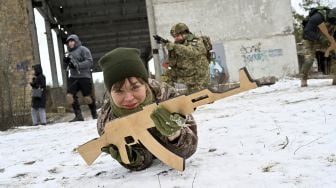 Pasukan Pertahanan Teritorial Ukraina yang merupakan cadangan militer Angkatan Bersenjata Ukraina, memegang replika kayu senapan Kalashnikov selama latihan militer di dekat Kiev, Ukraina, pada (25/12/2021). [SERGEI SUPINSKY / AFP]