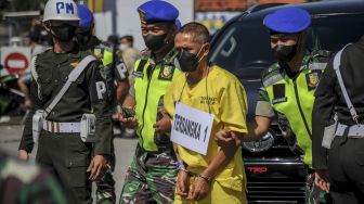 Petugas membawa tersangka dengan inisial P saat rekonstruksi kecelakaan tabrak lari di Jalan Nasional III, Desa Ciaro, Nagreg, Kabupaten Bandung, Jawa Barat, Senin (3/1/2022). [ANTARA FOTO/Raisan Al Farisi]