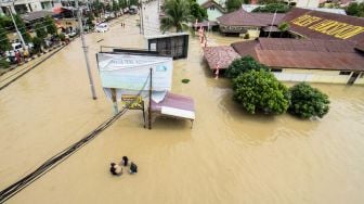 Sejumlah warga berjalan menembus banjir yang melanda Kota Lhoksukon, Aceh Utara, Aceh, Senin (3/1/2022). ANTARA FOTO/Rahmad
