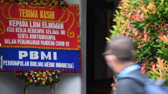 Seorang pria mengamati karangan bunga ucapan terima kasih kepada Lembaga Biologi Molekuler (LBM) Eijkman di Kantor LBM Eijkman Jakarta, Senin (3/1/2022). ANTARA FOTO/Wahyu Putro 

