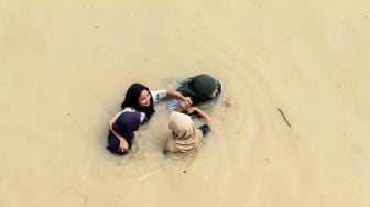 Sejumlah warga berjalan menembus banjir yang melanda Kota Lhoksukon, Aceh Utara, Aceh, Senin (3/1/2022). ANTARA FOTO/Rahmad
