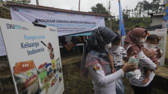 Petugas memberikan mainan kepada dua anak selama berlangsungnya program “BULOG Peduli Gizi” di Desa Purwosari, Kecamatan Sukorejo, Kabupaten Kendal, Jawa Tengah, Kamis (6/1/2021). [Suara.com/Angga Budhiyanto]