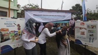 Petugas memberikan mainan kepada seorang anak selama berlangsungnya program “BULOG Peduli Gizi” di Desa Purwosari, Kecamatan Sukorejo, Kabupaten Kendal, Jawa Tengah, Kamis (6/1/2021). [Suara.com/Angga Budhiyanto]