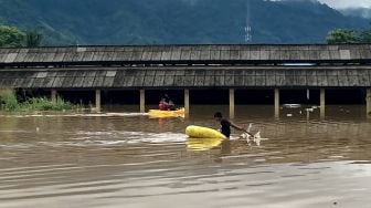 Seorang warga menaiki perahu saat banjir di Pasar Youtefa Abepura, Papua, Jumat (7/1/2022). ANTARA FOTO/Fredy Fakdawer
