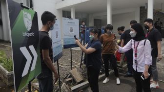 Penonton memindai kode batang dari aplikasi PeduliLindungi dalam kegiatan simulasi kehadiran penonton saat pertandingan basket di Hall Basket Senayan, Jakarta, Jumat (7/1/2022). [Suara.com/Angga Budhiyanto]