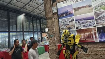 Pengamen mengenakan kostum robot Transformers menghibur pengunjung di Rest Area KM 260B Heritage-Banjaratma di ruas Tol Pejagan-Pemalang, Kabupaten Brebes, Jawa Tengah, Kamis (6/1/2021). [Suara.com/Angga Budhiyanto]