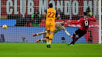 Pemain depan AC Milan Olivier Giroud (kanan) mencetak gol melalui penalti selama pertandingan sepak bola Serie A Italia AC Milan melawan AS Roma di stadion San Siro, Milan, Italia,  Jumat (7/1/2022) dini hari WIB. Miguel MEDINA / AFP