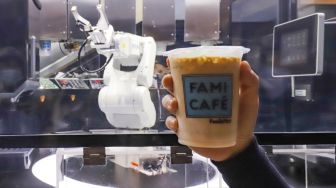 Pengunjung menunjukkan minuman kopi hasil buatan robot barista di salah satu toko ritel di Grand Indonesia, Jakarta Pusat, Sabtu (8/1/2022). [Suara.com/Alfian Winanto]