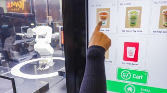 Pengunjung memesan minuman kopi untuk dibuat oleh robot barista di salah satu toko ritel di Grand Indonesia, Jakarta Pusat, Sabtu (8/1/2022). [Suara.com/Alfian Winanto]