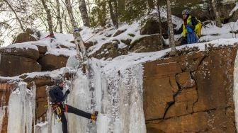 Pendaki memanjat dinding batu yang ditutupi pilar es selama Festival Panjat Tebing Es Sandstone, Minnesota, Amerika Serikat, pada (8/1/2022). [KEREM YUCEL / AFP]