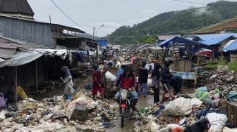 Sejumlah warga melintasi tumpukan sampah akibat banjir di Pasar Youtefa, Abepura, Jayapura, Papua, Minggu (9/1/2022). [ANTARA FOTO/Adharnazamudin]