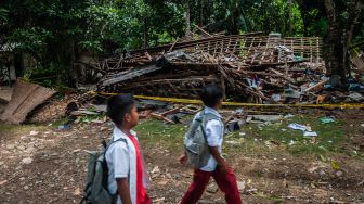 Pelajar melintas di depan rumah yang hancur akibat bom ikan di Kampung Cisaat, Pandeglang, Banten, Selasa (11/1/2022). ANTARA FOTO/Muhammad Bagus Khoirunas
