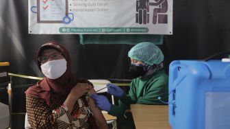 Vaksinator menyuntikkan vaksin COVID-19 dosis ketiga kepada warga saat vaksinasi booster COVID-19 di Puskesmas Kecamatan Kramat Jati, Jakarta, Rabu (12/1/2022). [Suara.com/Angga Budhiyanto]