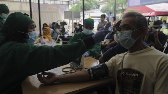 Tenaga kesehatan memeriksa kesehatan warga yang akan mendapatkan vaksin COVID-19 dosis ketiga di Puskesmas Kecamatan Kramat Jati, Jakarta, Rabu (12/1/2022). [Suara.com/Angga Budhiyanto]