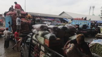 Buruh angkut membawa sayuran dan buah ke dalam truk di Pasar Induk Kramat Jati, Jakarta, Rabu (12/1/2022). [Suara.com/Angga Budhiyanto]