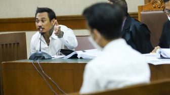 Musisi I Gede Ari Astina atau Jerinx SID mengajukan pertanyaan kepada Adam Deni yang hadir sebagai saksi saat sidang kasus pengancaman di Pengadilan Negeri Jakarta Pusat, Rabu (12/1/2022). [Suara.com/Alfian Winanto]