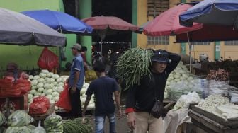 Pembeli membawa sayuran di Pasar Induk Kramat Jati, Jakarta, Rabu (12/1/2022). [Suara.com/Angga Budhiyanto]