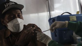 Vaksinator menyuntikkan vaksin COVID-19 dosis ketiga kepada warga saat vaksinasi booster COVID-19 di Puskesmas Kecamatan Kramat Jati, Jakarta, Rabu (12/1/2022). [Suara.com/Angga Budhiyanto]