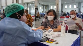Petugas memeriksa kesehatan calon penerima vaksin booster COVID-19 di Jogja Expo Center, Bantul, DI Yogyakarta, Kamis (13/1/2022).  ANTARA FOTO/Hendra Nurdiyansya
