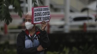 Massa yang tergabung dalam Aliansi Rakyat Menggugat (ARM) membawa poster saat melakukan aksi unjuk rasa di sekitar Gedung Komisi Pemberantasan Korupsi (KPK), Jakarta, Kamis (13/1/2022). [Suara.com/Angga Budhiyanto]