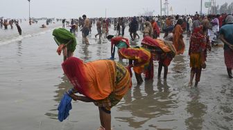 Peziarah Hindu mencuci pakaian mereka setelah berenang suci di pertemuan Gangga dan Teluk Benggala selama Gangasagar Mela pada kesempatan Makar Sankranti di Pulau Sagar, India, pada (14/1/2022). [DIBYANGSHU SARKAR / AFP]