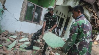 Warga dibantu personel TNI membersihkan bangunan rumahnya yang rusak di Sumur, Pandeglang, Banten, Sabtu (15/1/2022). [ANTARA FOTO/Muhammad Bagus Khoirunas]