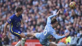 Gelandang Manchester City Jack Grealish (kanan) terjatuh setelah berhadapan dengan bek Chelsea Cesar Azpilicueta selama pertandingan sepak bola Liga Premier Inggris antara Manchester City dan Chelsea di Stadion Etihad, Manchester, Inggris, Sabtu (15/1/2022). [OLI SCARFF / AFP]