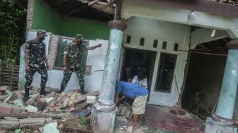 Warga dibantu personel TNI membersihkan bangunan rumahnya yang rusak di Sumur, Pandeglang, Banten, Sabtu (15/1/2022). [ANTARA FOTO/Muhammad Bagus Khoirunas]