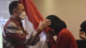 Anggota Timnas Sepak Bola Putri Indonesia mencium bendera merah putih disaksikan Ketua Umum PSSI Mochamad Iriawan (kiri) pada prosesi pelepasan tim di Jakarta, Minggu (16/1/2022). [ANTARA FOTO/Indrianto Eko Suwarso]