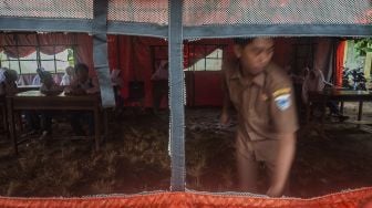 Suasana kegiatan belajar mengajar di dalam tenda sementara di MTs Mathlahul Anwar Sumur, Pandeglang, Banten, Senin (17/1/2022). [ANTARA FOTO/Muhammad Bagus Khoirunas]