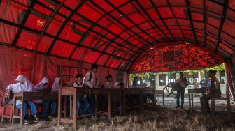 Suasana kegiatan belajar mengajar di dalam tenda sementara di MTs Mathlahul Anwar Sumur, Pandeglang, Banten, Senin (17/1/2022). [ANTARA FOTO/Muhammad Bagus Khoirunas]