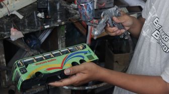 Andy Kunaryo (34) menyelesaikan pembuatan miniatur bus di Workshop Belang Bentong, Limo, Depok, Jawa Barat, Senin (17/1/2022). [Suara.com/Septian]