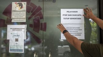 Petugas memasang informasi masyarakat di Kantor Kelurahan Gondangdia, Jakarta, Rabu (19/1/2022).  ANTARA FOTO/Muhammad Adimaja