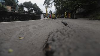 Petugas Suku Dinas Bina Marga Jakarta Pusat memperbaiki jalan ambles di Jalan Inspeksi Kali Ciliwung, Kenari, Kecamatan Senen, Jakarta, Rabu (19/1/2022). [Suara.com/Angga Budhiyanto]