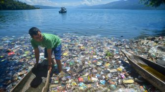 Warga memindahkan biduk di antara sampah di tepian Danau Singkarak, Nagari Sumpu, Kabupaten Tanah Datar, Sumatera Barat, Kamis (20/1/2022).ANTARA FOTO/Iggoy el Fitra