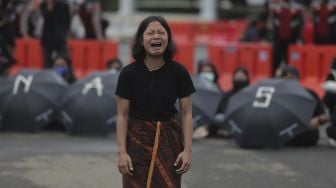 Massa yang tergabung dalam Jaringan Solidaritas Korban untuk Keadilan (JSKK) melakukan aksi teatrikal selama aksi Kamisan Ke-714 di seberang Istana Merdeka, Jakarta, Kamis (20/1/2022). [Suara.com/Angga Budhiyanto]