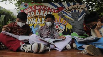 Anak-anak membaca buku di pustaka mini Bale Buku di Kelurahan Dukuh, Kramat Jati, Jakarta, Kamis (20/1/2022). [Suara.com/Angga Budhiyanto]