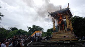 Wisatawan mengabadikan prosesi pembakaran peti berbentuk lembu yang berisi jenazah Raja Pemecutan XI Anak Agung Ngurah Manik Parasara saat upacara ngaben di Denpasar, Bali, Jumat (21/1/2022). ANTARA FOTO/Nyoman Hendra Wibowo
