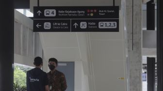 Petugas berdiri di bawah papan petunjuk arah atau &#039;wayfinding&#039; di Halte Integrasi CSW, Kebayoran Baru, Jakarta, Jumat (21/1/2022). [Suara.com/Angga Budhiyanto]