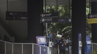 Petugas berdiri di bawah papan petunjuk arah atau 'wayfinding' di Halte Integrasi CSW, Kebayoran Baru, Jakarta, Jumat (21/1/2022). [Suara.com/Angga Budhiyanto]