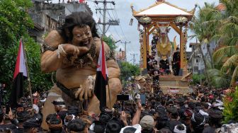 Umat Hindu mengarak ogoh-ogoh dan peti berbentuk lembu dalam upacara ngaben Raja Pemecutan XI Anak Agung Ngurah Manik Parasara di Denpasar, Bali, Jumat (21/1/2022). ANTARA FOTO/Nyoman Hendra Wibowo