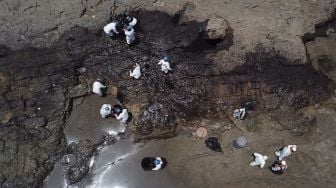 Foto udara petugas membersihkan tumpahan minyak dari pantai di Provinsi Callao, Peru, pada (17/1/2022). [CRIS BOURONCLE / AFP]