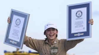 Pilot remaja Belgia-Inggris Zara Rutherford berdiri memegang sertifikat di atas pesawat Ultralight Shark setelah mendarat kembali di akhir perjalanan solo keliling dunianya di Kota Kortrijk, Belgia, pada (20/1/2022). [JOHN THYS / AFP]