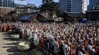 Anggota Ordo Jogye, sekte Buddha terbesar di Korea Selatan, berdoa saat mengadakan rapat umum di Kuil Jogye, Seoul, Jumat (21/1/2022). [ANTHONY WALLACE / AFP]