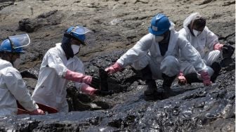 Petugas membersihkan tumpahan minyak dari pantai di Provinsi Callao, Peru, pada (17/1/2022). [CRIS BOURONCLE / AFP]