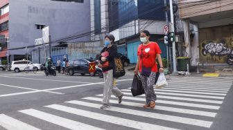 Warga menyeberang melalui pelican crossing di Kawasan Glodok, Jakarta Barat, Minggu (23/1/2022). [Suara.com/Alfian Winanto]