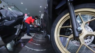 Petugas membersihkan sepeda motor yang di panjang di salah satu dealer di kawasan Pasar Minggu, Jakarta Selatan, Minggu (23/1/2022). [Suara.com/Alfian Winanto]