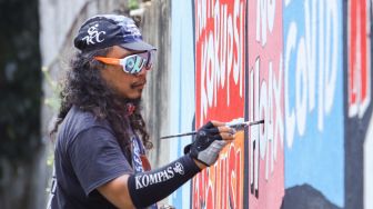 Pekerja seni membuat mural di kawasan Palmerah, Jakarta Pusat, Minggu (23/1/2022). [Suara.com/Alfian Winanto]